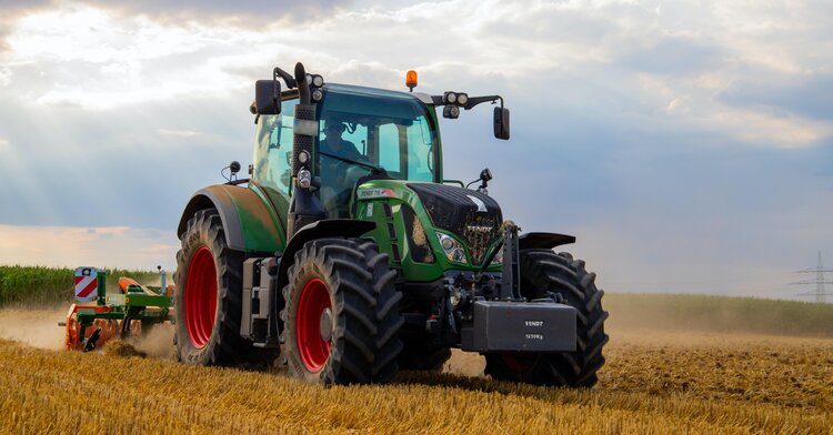 large green tractor ploughing through field
