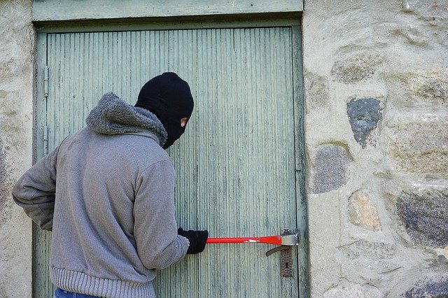 burglar using a crowbar on a door